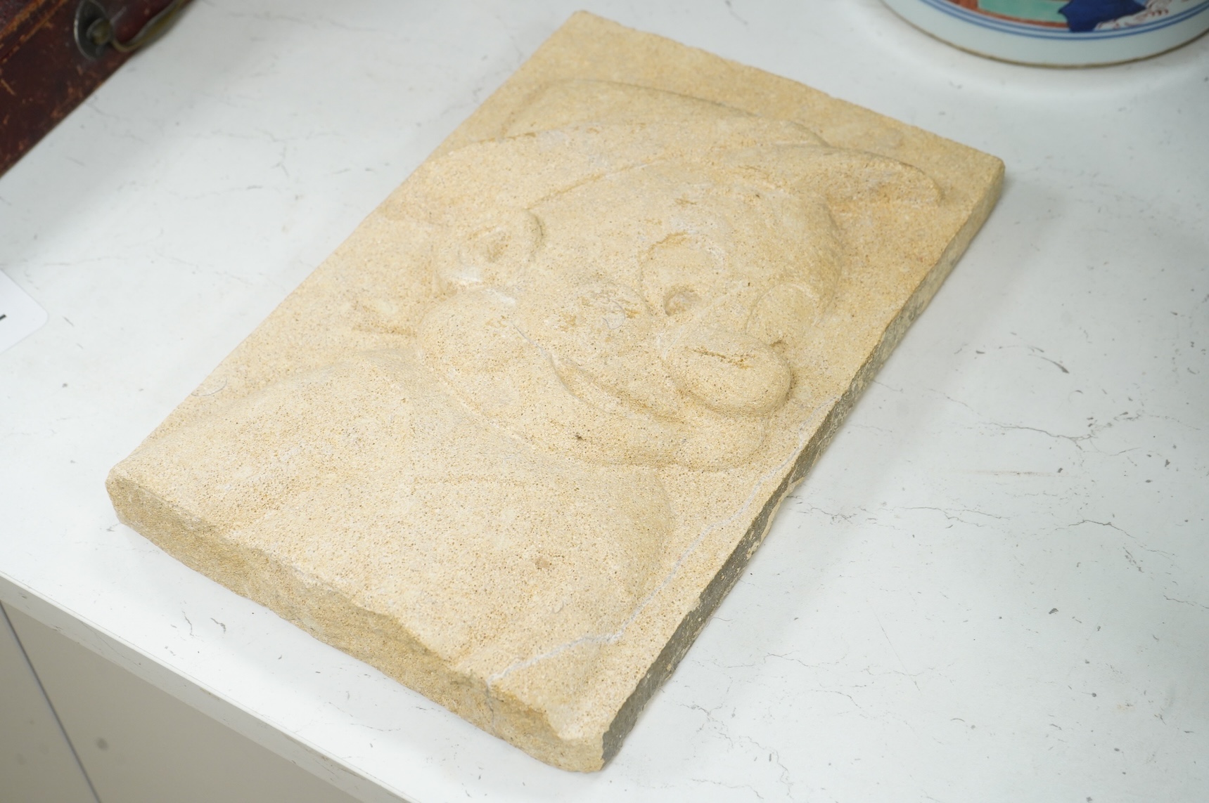 A rectangular carved sandstone panel depicting Pinocchio (Provenance, formally from the façade of Thomas Biles stonemasons building, Corn street, Whitney, Oxon, 1868-1957)